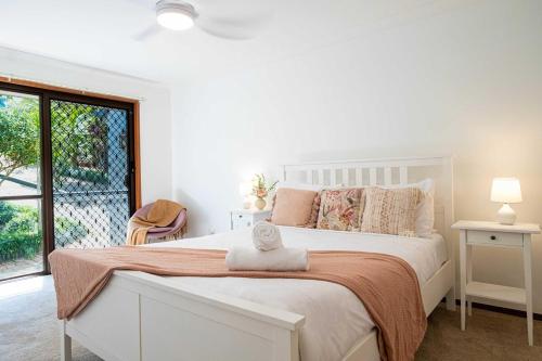 a white bedroom with a bed with a towel on it at Mountain Retreat Scenic Getaway with BBQ in Mount Tamborine
