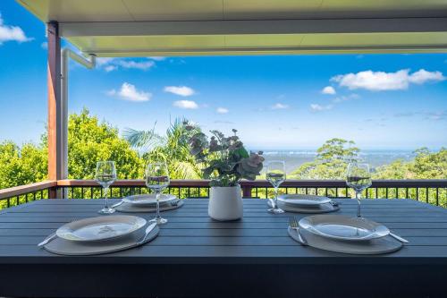 a table with plates and wine glasses on a balcony at Mountain Retreat Scenic Getaway with BBQ in Mount Tamborine