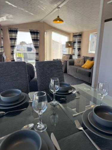 a dining table with plates and wine glasses on it at Golden Palm Resort - The Meridian - Coastal Caravan Breaks in Chapel Saint Leonards