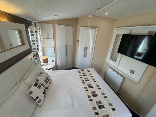a bedroom with a white bed and a flat screen tv at Golden Palm Resort - The Meridian - Coastal Caravan Breaks in Chapel Saint Leonards