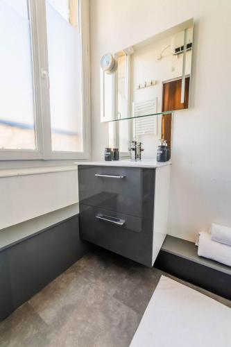 une salle de bain avec un lavabo et un miroir dans l'établissement Dalissimo - 1 Chambre, à Brive-la-Gaillarde