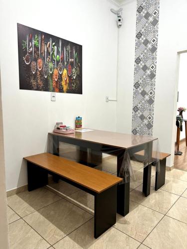 a desk with a bench and a painting on the wall at Quartos para alugar em itu Hostel Jm in Itu
