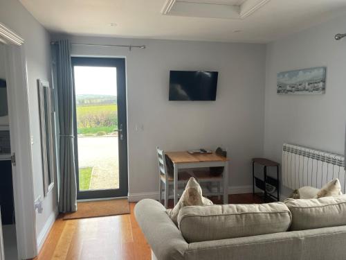 a living room with a couch and a table and a window at The Captain's Retreat, Quiet 1 Bed Dog Friendly in Puncknowle