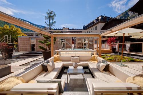 an outdoor patio with couches and a pool at Backstage Boutique SPA Hotel in Zermatt