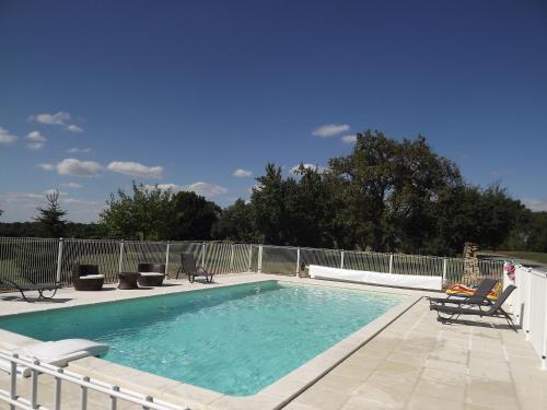 a swimming pool with two chairs and a fence at Logis De La Mélissière in Xaintray