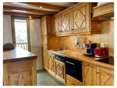 une cuisine avec des armoires en bois et un évier dans l'établissement Appartement lumineux Courchevel - 6 pers, 3 ch, parking, près des pistes - FR-1-514-88, à Courchevel
