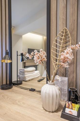 a vase with flowers on a table in front of a mirror at Polyzos Luxury Suites Meteora #7 - Adults Friendly in Kalabaka