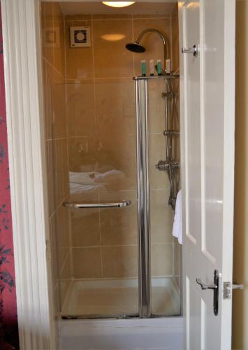 a shower with a glass door in a bathroom at Town House Rooms in Hastings