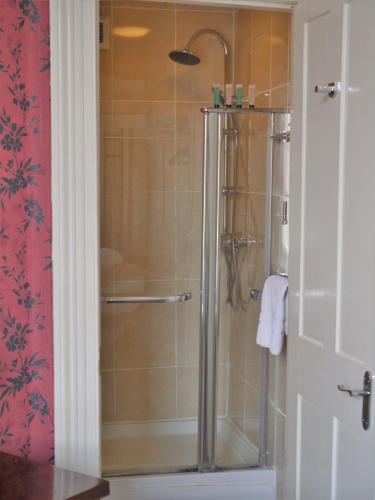 a shower with a glass door in a bathroom at Town House Rooms in Hastings