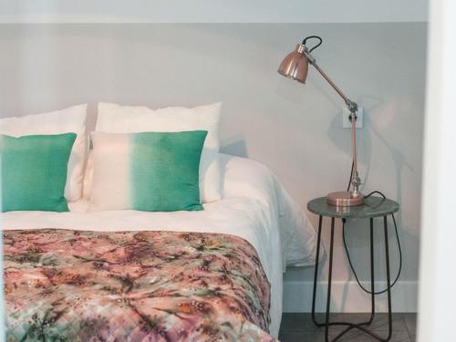 1 dormitorio con 1 cama con almohadas verdes y lámpara en Hostal La Casa Sanlúcar, en Sanlúcar de Barrameda