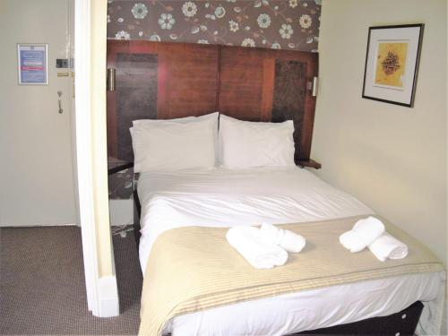 a hotel room with a bed with towels on it at Town House Rooms in Hastings