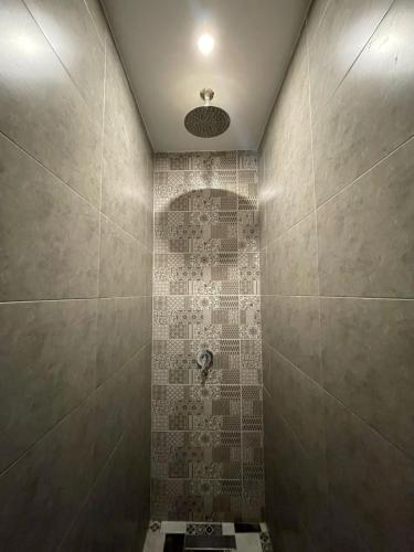 a bathroom with a shower with a tile wall at Playa Del Sol Surf House in Tamraght Ouzdar