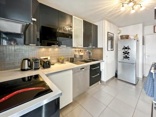 - une cuisine avec des armoires en noir et blanc et un réfrigérateur dans l'établissement Charmant logement avec vue jardin - proche du métro, à Asnières-sur-Seine