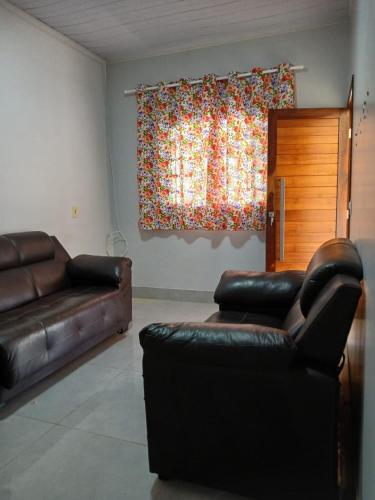 a living room with two leather couches and a window at Casadapraça in Goianésia