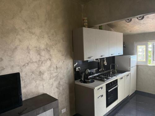 a kitchen with white cabinets and a stove top oven at Villettine le Marie in Ricadi