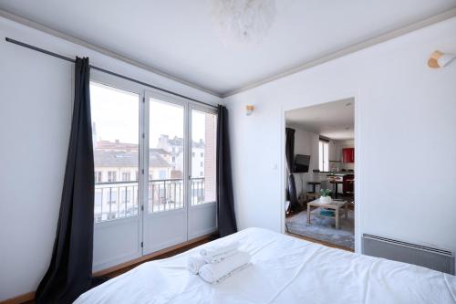 une chambre avec un lit blanc et une grande fenêtre dans l'établissement Charmant T3 au Cœur de Lyon 7ème, à Lyon