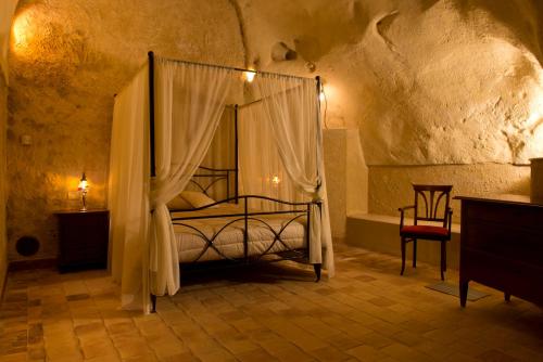 een slaapkamer met een hemelbed en een stoel bij Sassisuite in Matera
