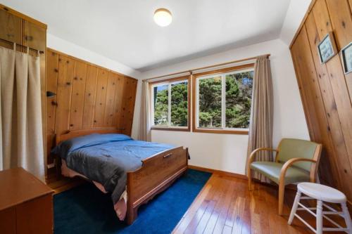 a bedroom with a bed and a chair and a window at Cottage By The Sea Nedonna Beach Getaway in Rockaway Beach