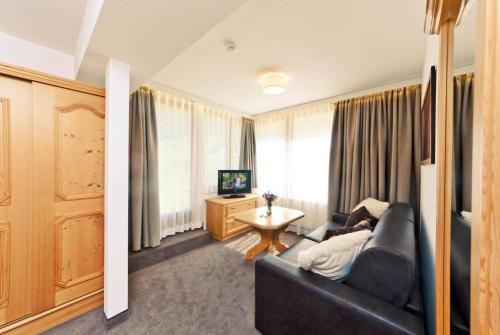 a living room with a black couch and a television at Waldpark Hotel Garni in Samnaun
