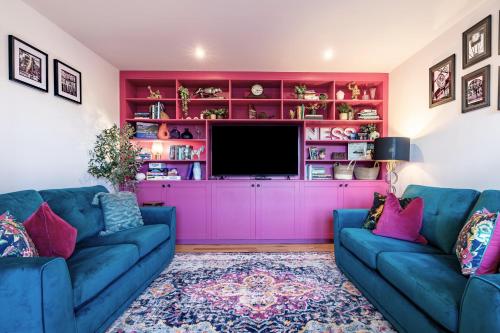 a living room with two blue couches and a pink wall at Ness in the City in Inverness