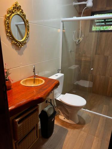 a bathroom with a toilet and a sink and a mirror at Bangalô império verde in Chã Grande