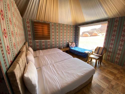 a bedroom with a bed and a chair and a window at Lowrance luxury camp in Wadi Rum
