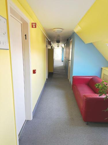 a long hallway with a red couch in a room at Family Hôtel in Wavre