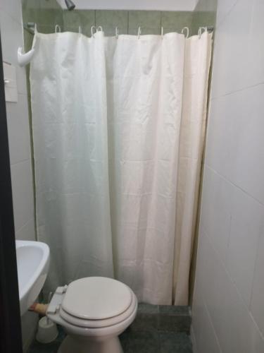 a bathroom with a toilet and a white shower curtain at Tinta Roja Residencia Estudiantil in Buenos Aires
