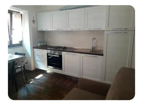 a kitchen with white cabinets and a stove top oven at Casa Mangiafuoco in Vernante