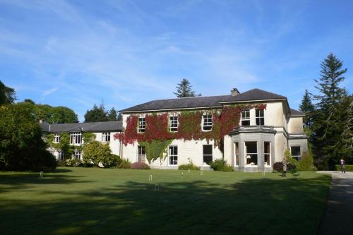 Una gran casa blanca con hiedra roja. en Currarevagh House en Oughterard