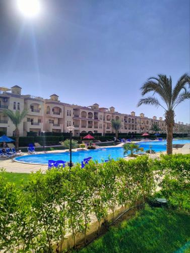 - une vue sur la piscine du complexe bordée de palmiers et de bâtiments dans l'établissement شاليه للايجار في العين السخنة قرية بالم بيتش للعائلات فقط, à Ain Sokhna