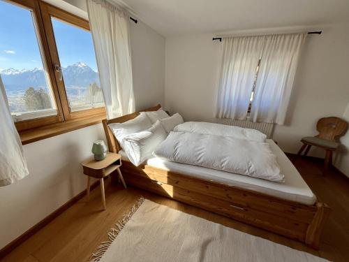 a bedroom with a bed with white sheets and a window at Chalet mit Bergblick & Sauna in Pill