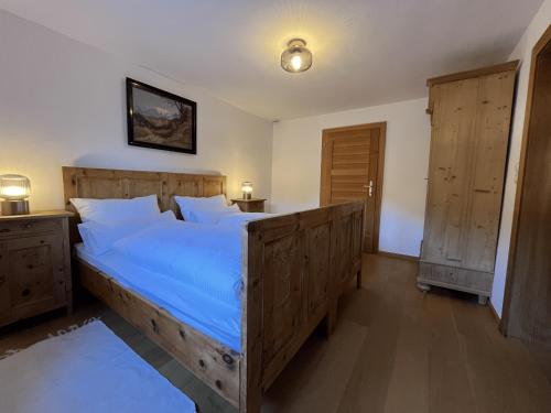a bedroom with a large wooden bed with blue sheets at Chalet mit Bergblick & Sauna in Pill