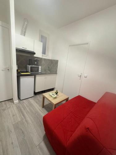 un salon avec un canapé rouge et une cuisine dans l'établissement Ciel Bleu - Premier étage - Centre ville, à Clermont-Ferrand
