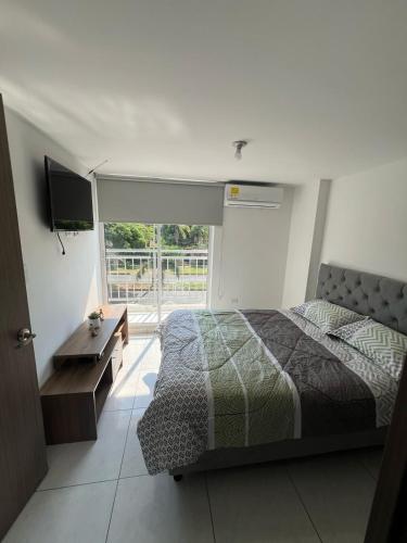 a bedroom with a bed and a tv and a window at Apartamento Mirador del Valle in Valledupar