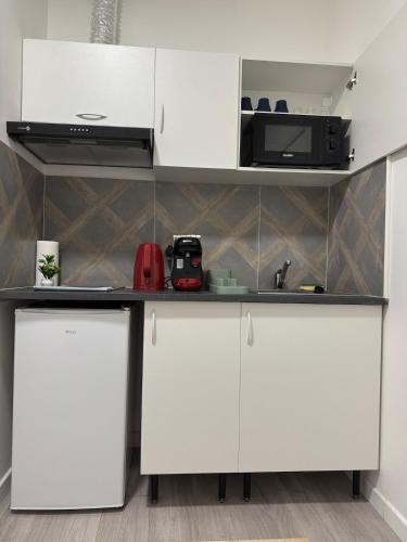 une cuisine avec des armoires blanches et un micro-ondes dans l'établissement Soleil Rose, à Clermont-Ferrand