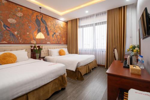 a hotel room with two beds and a desk at Thuy Duong Boutique Hotel Hue in Hue