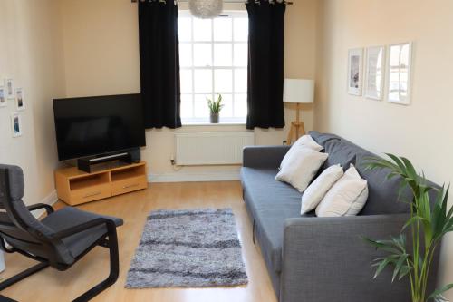 a living room with a blue couch and a television at Scandinavian City Centre Apartment in Worcester