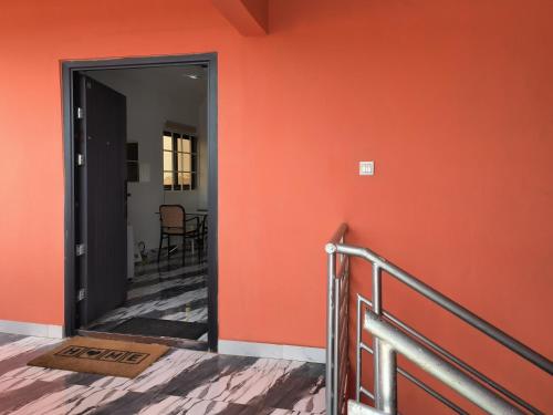 a hallway with an orange wall and a doorway at Empress White House Accra in Tema