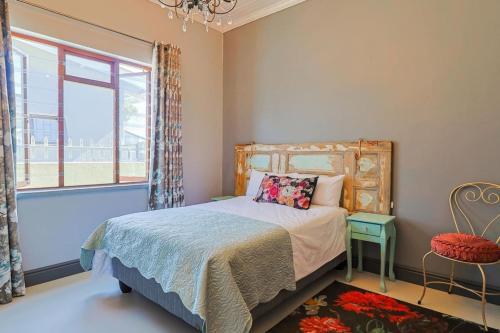 a bedroom with a bed and a window and a chair at Bietjie Sjiek - cozy stay, big breakaway in Kleinmond