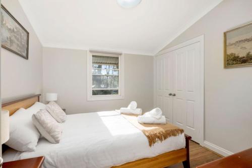 a white bedroom with a large bed with white pillows at Seaside Escape in North Arm Cove