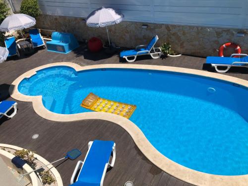 a swimming pool with chairs and umbrellas on a deck at Vila Luisa Anabela Piscine et Jacuzzi only family in Albufeira
