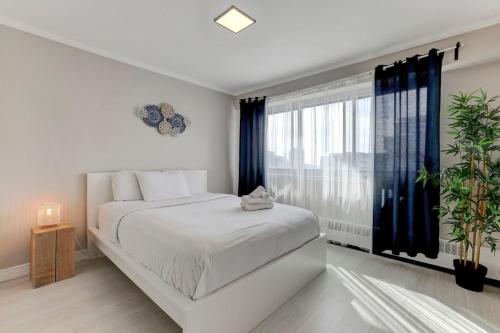 a bedroom with a white bed and a large window at Amazing 1-bedroom apartment in MTL Downtown in Montréal