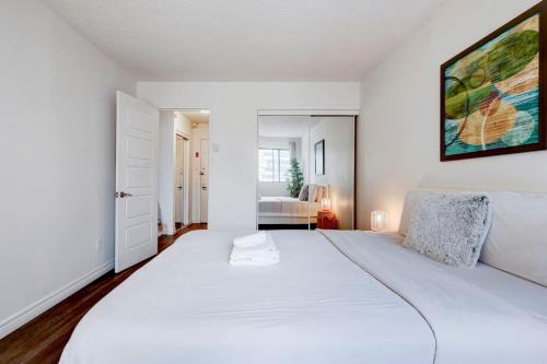 a white bedroom with a large white bed in it at Inviting 1BR on Rene Levesque in Montréal