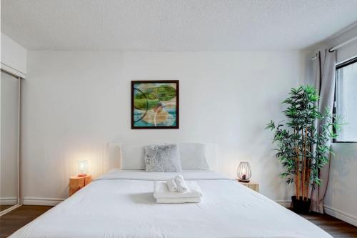 a white bedroom with a bed with a towel on it at Inviting 1BR on Rene Levesque in Montréal