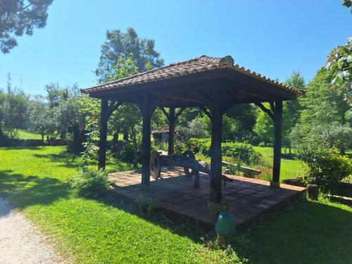 a wooden gazebo with a bench in a park at Quinta das Carvalhas in Neiva