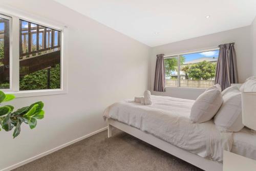 a white bedroom with a bed and two windows at Ground floor apartment in Taupo