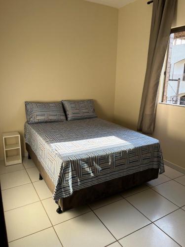 a bedroom with a bed in a room with a window at Apartamento Central em Alfenas in Alfenas
