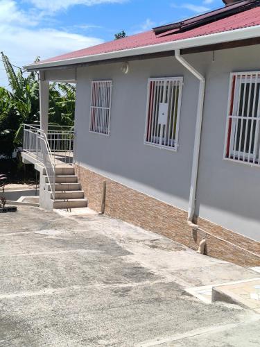 a white house with a staircase in front of it at Gite Beauvallon in Basse-Terre