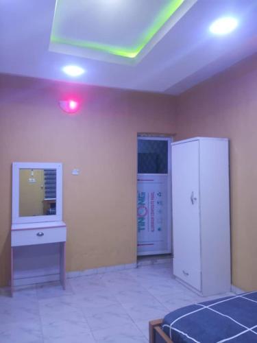 a room with a bed and a desk and a tv at Fehintola Apartment in Abeokuta